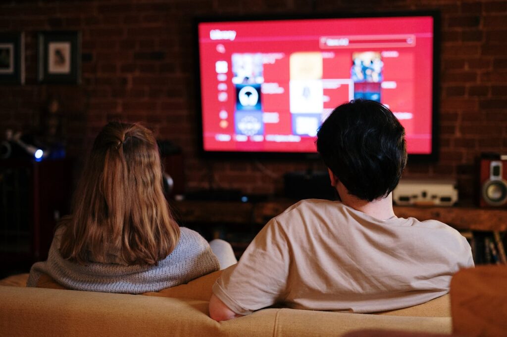 pexels photo 4009409 A couple enjoys streaming shows on a large TV in a cozy, brick-walled living room.